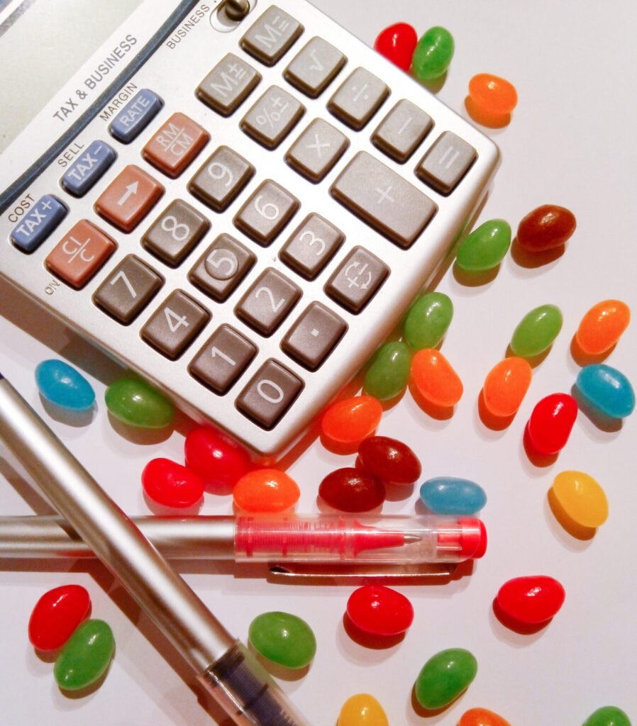A calculator and pen on a desk surrounded by jelly beans