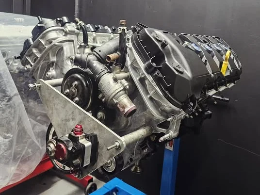 A V8 engine on a stand under the Downlow sign