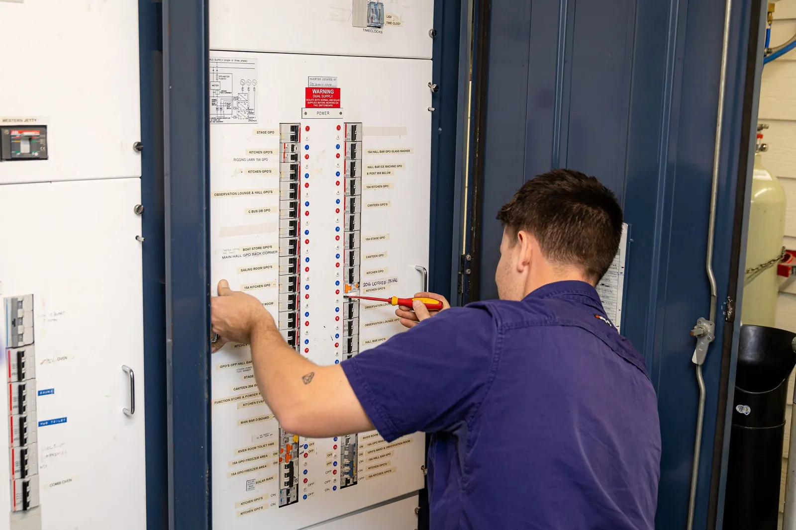 A Handcock electrician working on a large switchboard