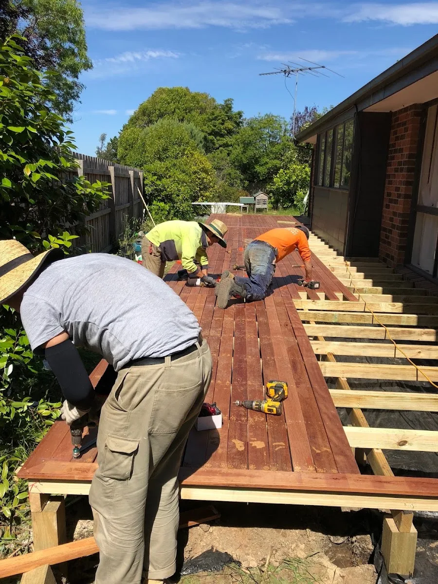 Carpenters fixing merbau boards to a new deck frame