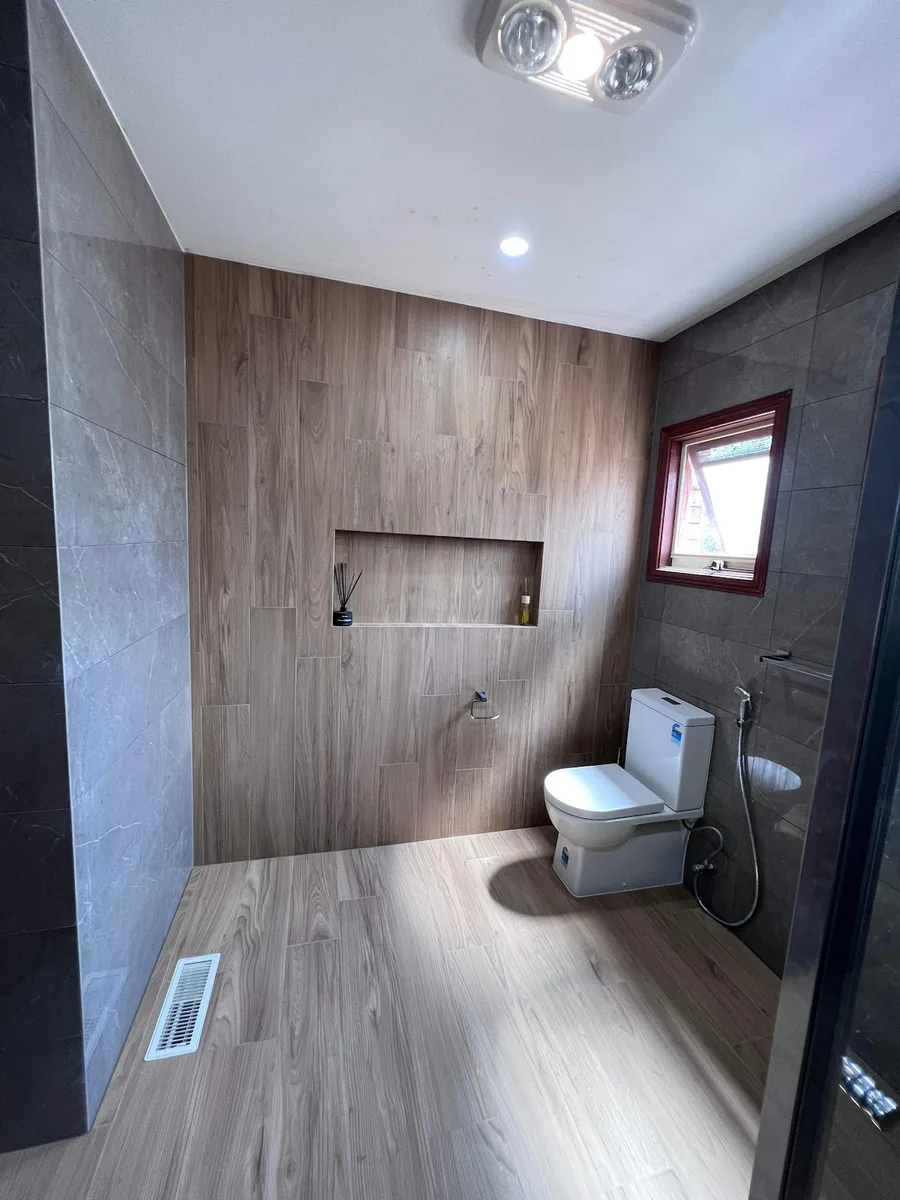 A bathroom with timber look wall and floor tiles and a recessed niche