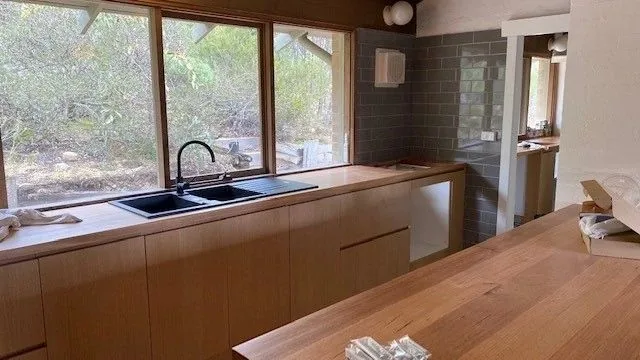 Timber kitchen with a black sink and a grey tiled splashback