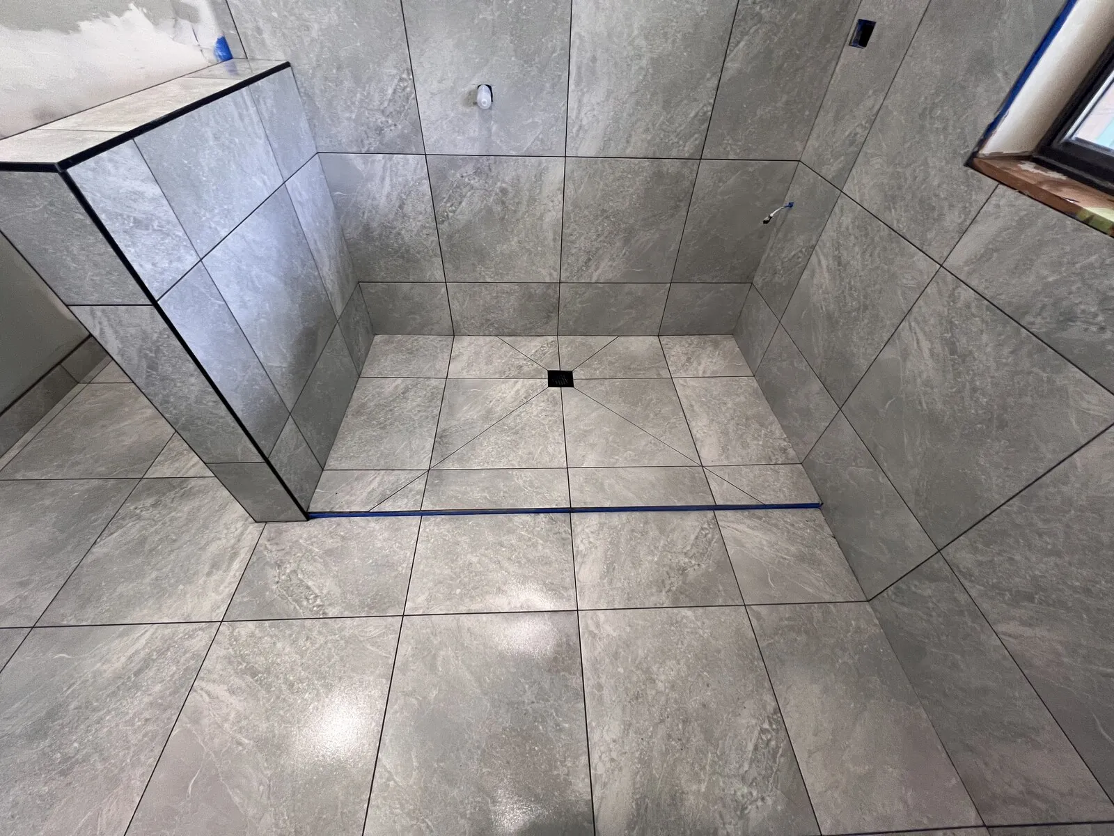 A grey tiled shower floor cut to fall to a centre waste