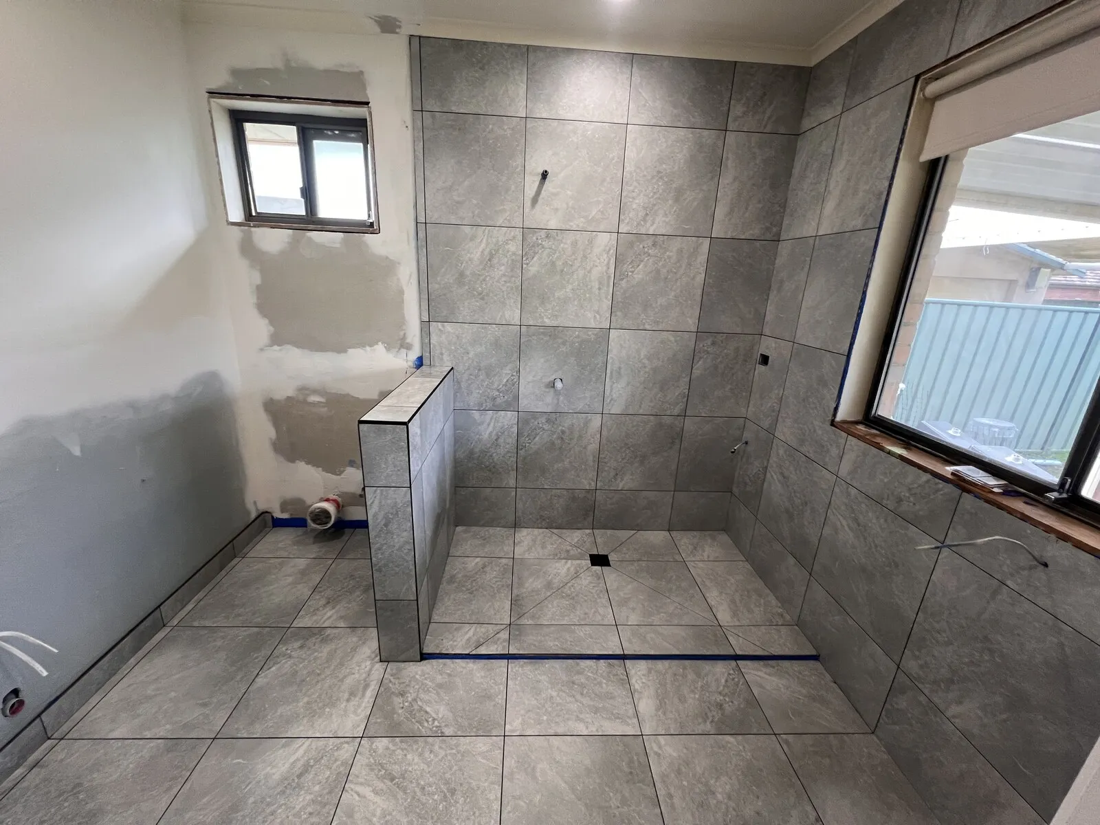 A bathroom tiled floor to ceiling in grey stone look tiles
