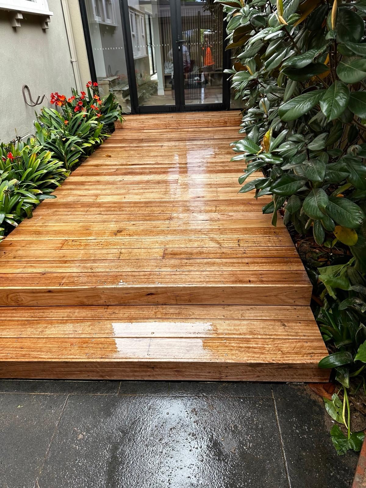 New timber deck path laid between dense planting at a rear entrance