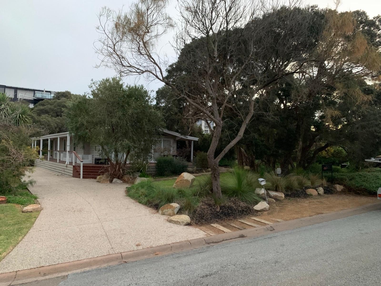 Coastal home street frontage with native garden, boulders and exposed-aggregate driveway
