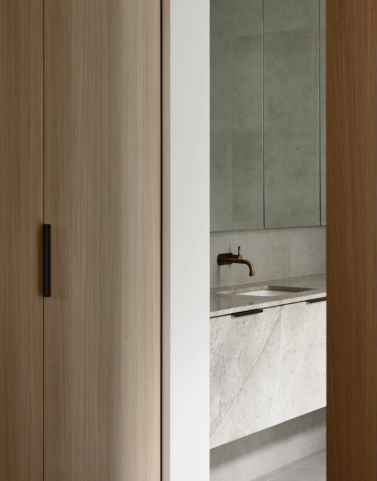 Stone bathroom with hidden-fixing cabinetry at Norman Ave — where trade sequence protects the finish
