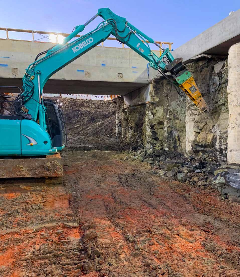 QCS excavator carrying out structural excavation and demolition beneath a bridge structure