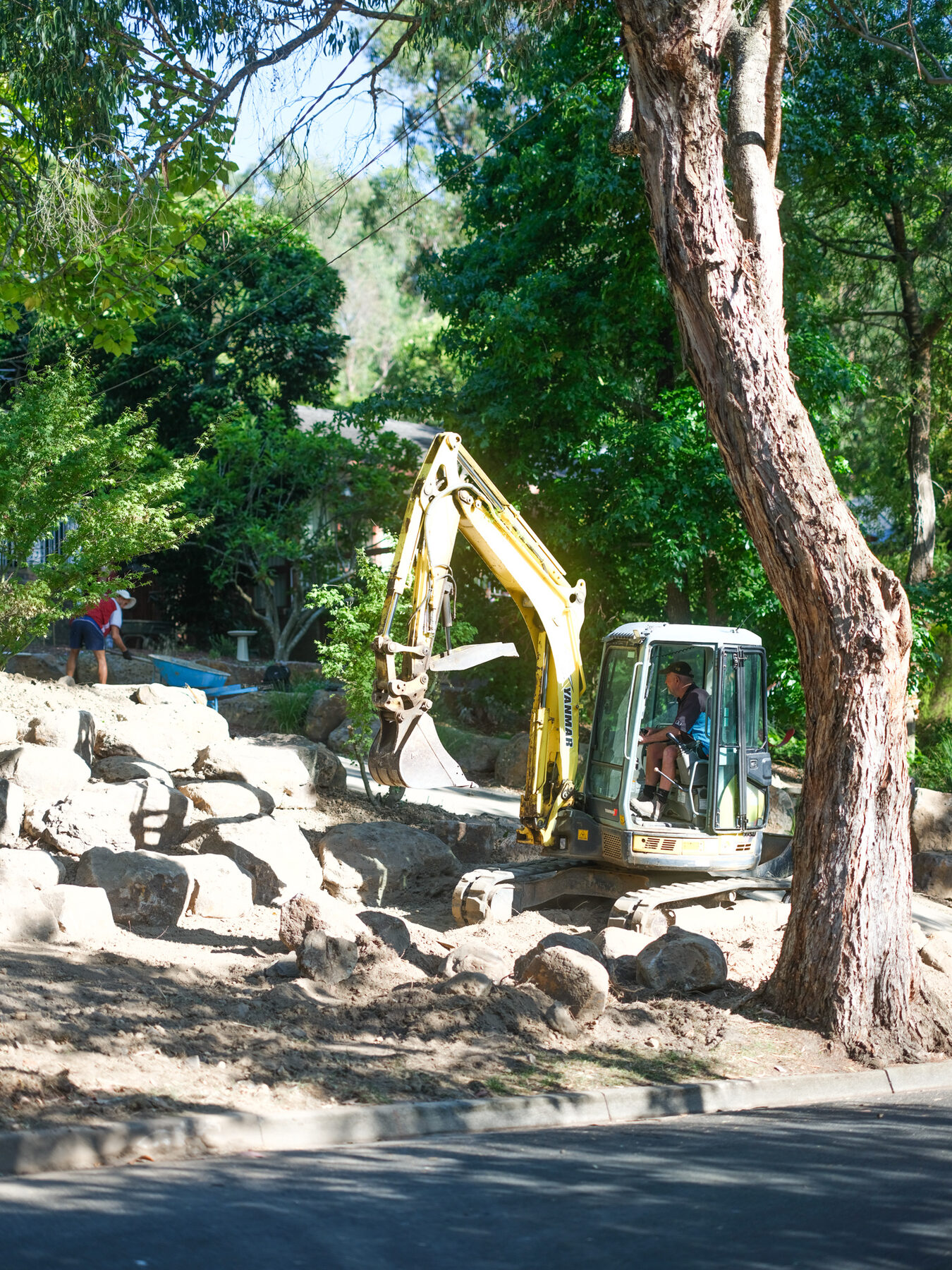 Excavator placing rocks for a terraced front garden