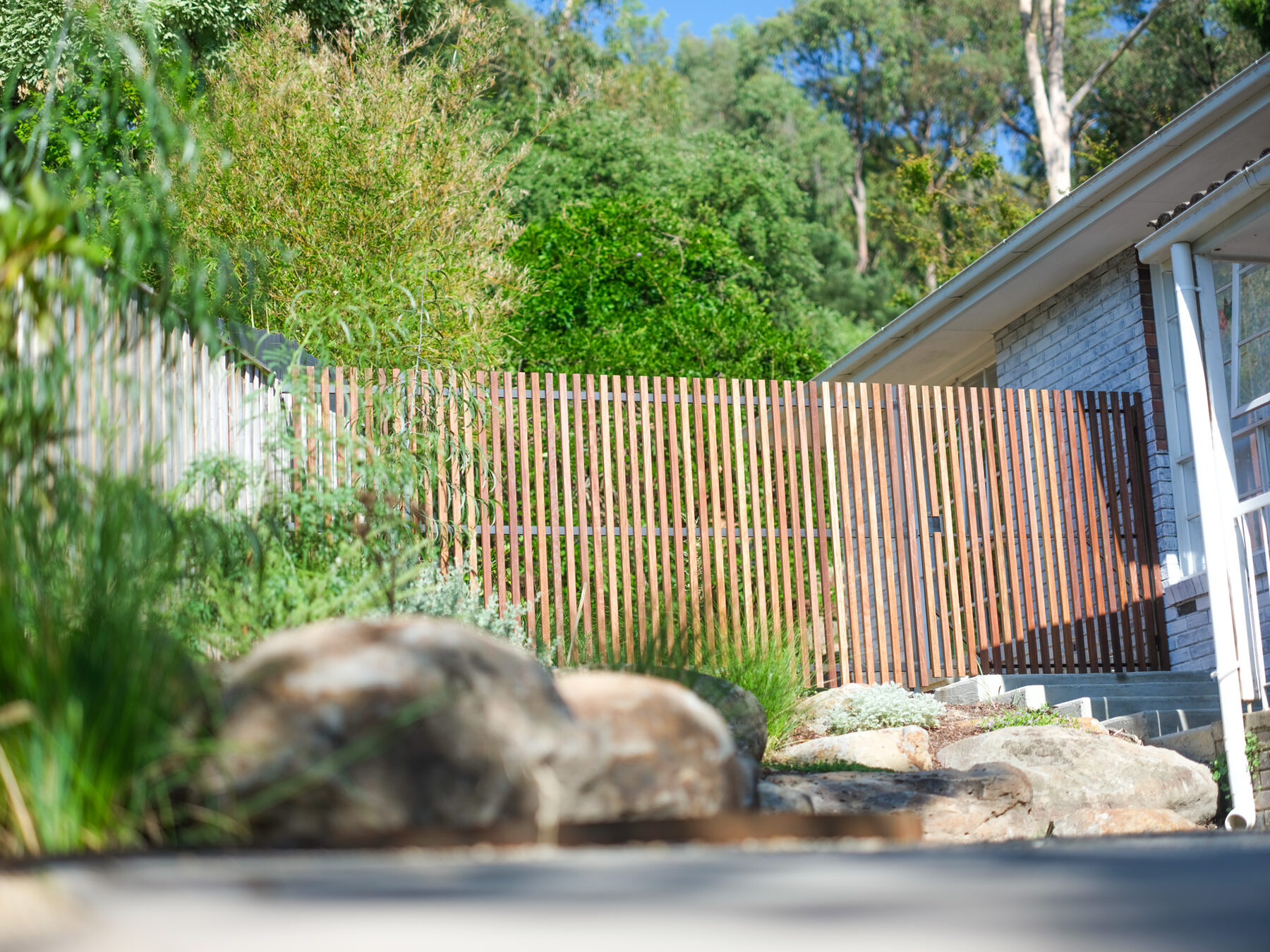 Hardwood slat fence running above a rock garden