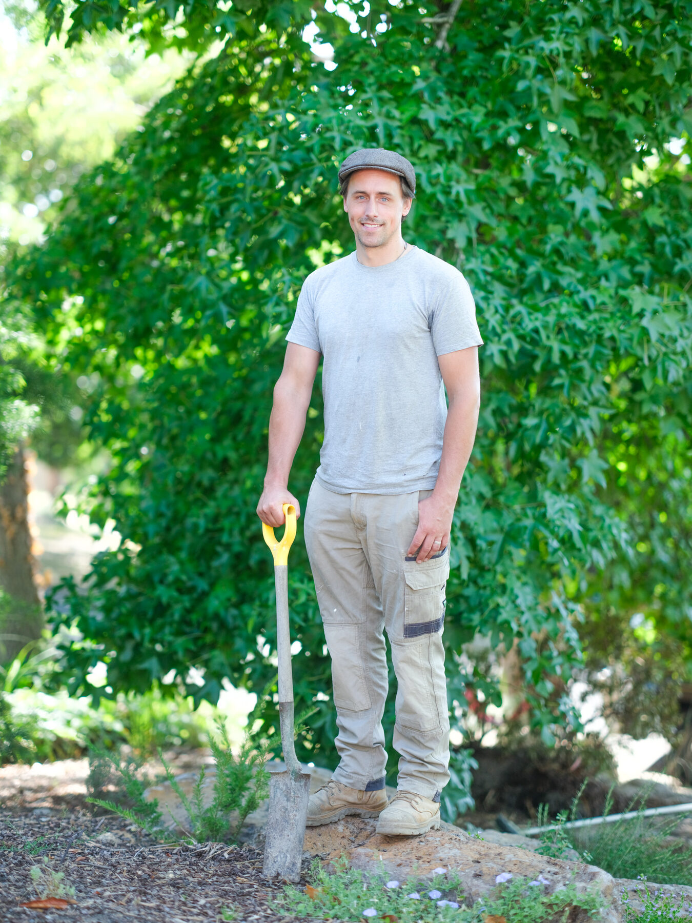 Ollie Macindoe, landscaper and founder of Unfurl Space Creations, standing in a garden with a spade