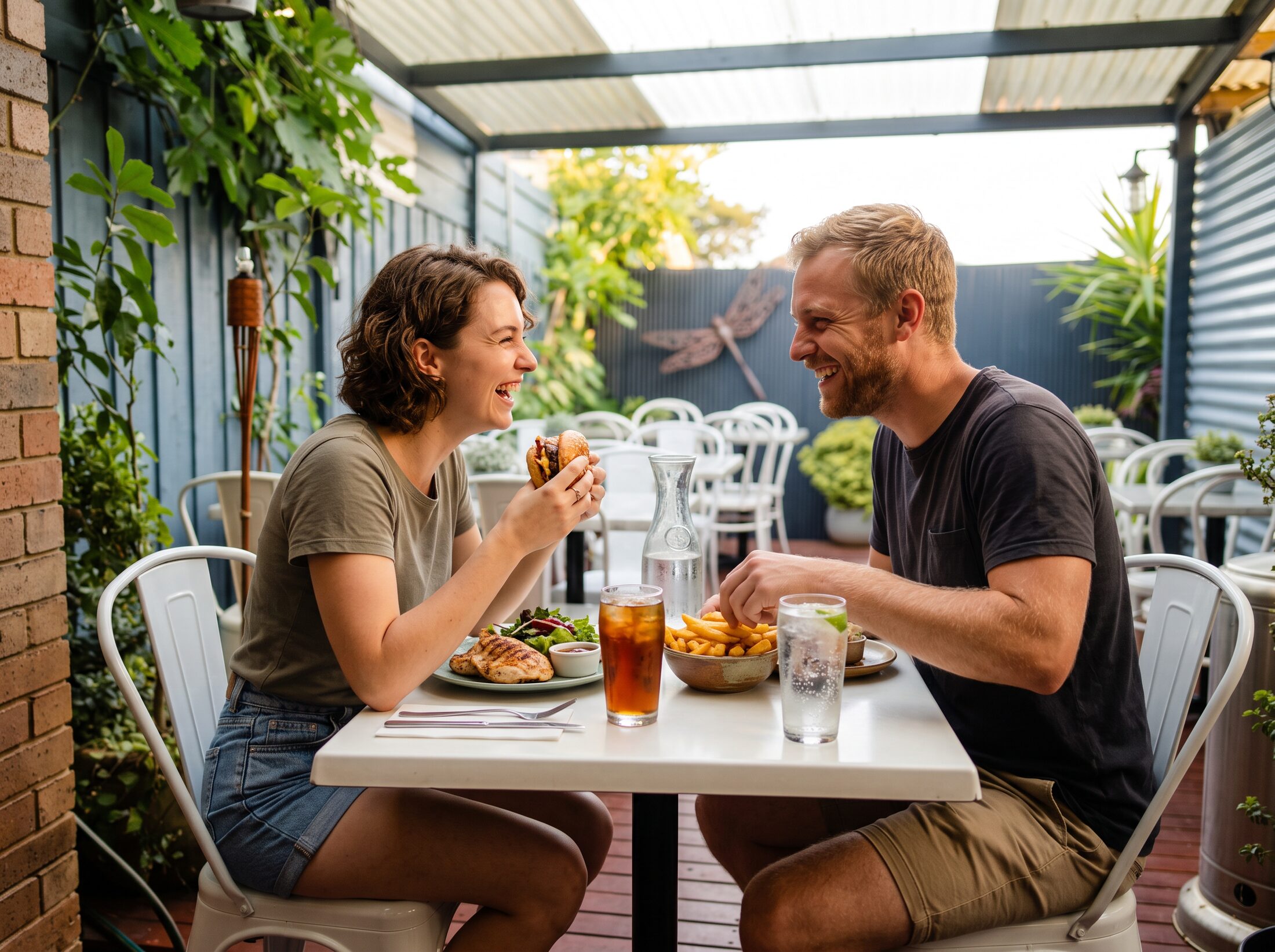 A couple sharing grilled chicken and a burger in the courtyard