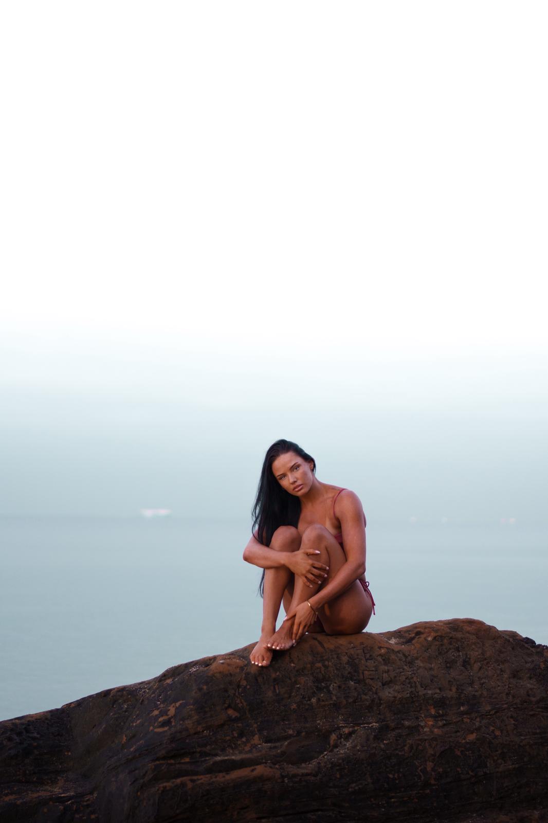 Woman seated on a rock over a misty cool ocean