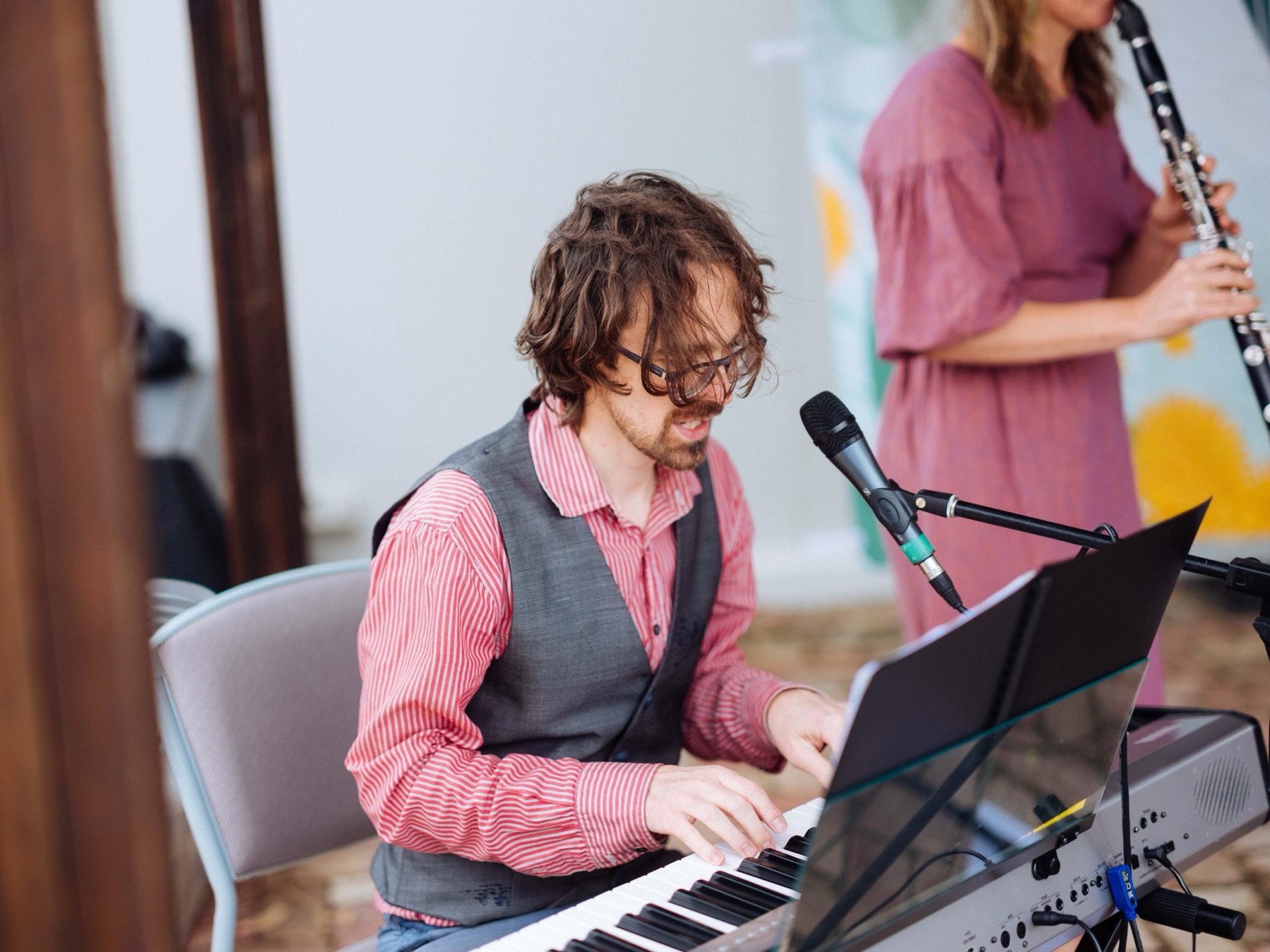 A musician playing keyboard and singing beside a clarinet player