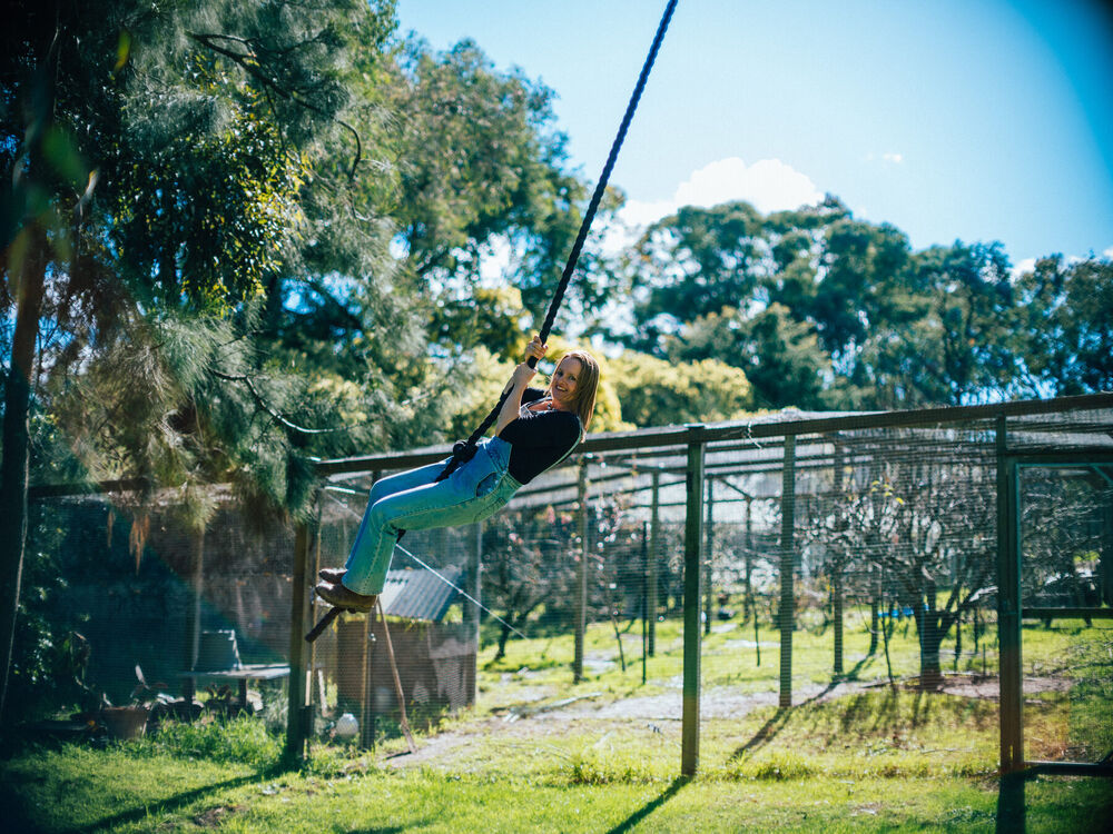 Rachel swinging out across the garden on a rope swing, laughing back at the camera