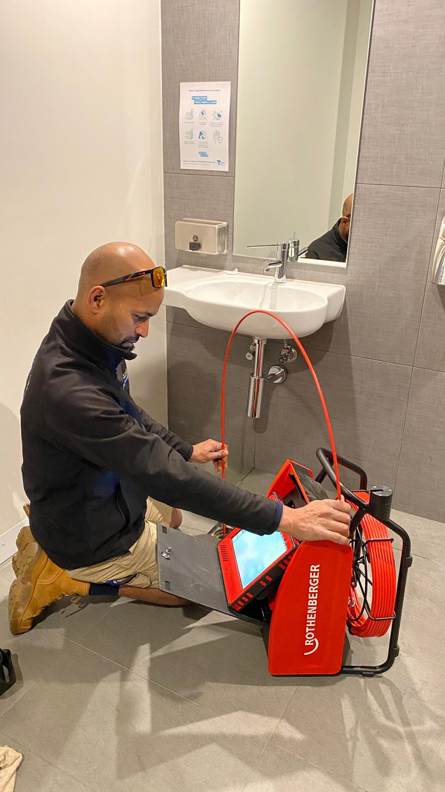 Asif working on site with drain clearing equipment in a bathroom
