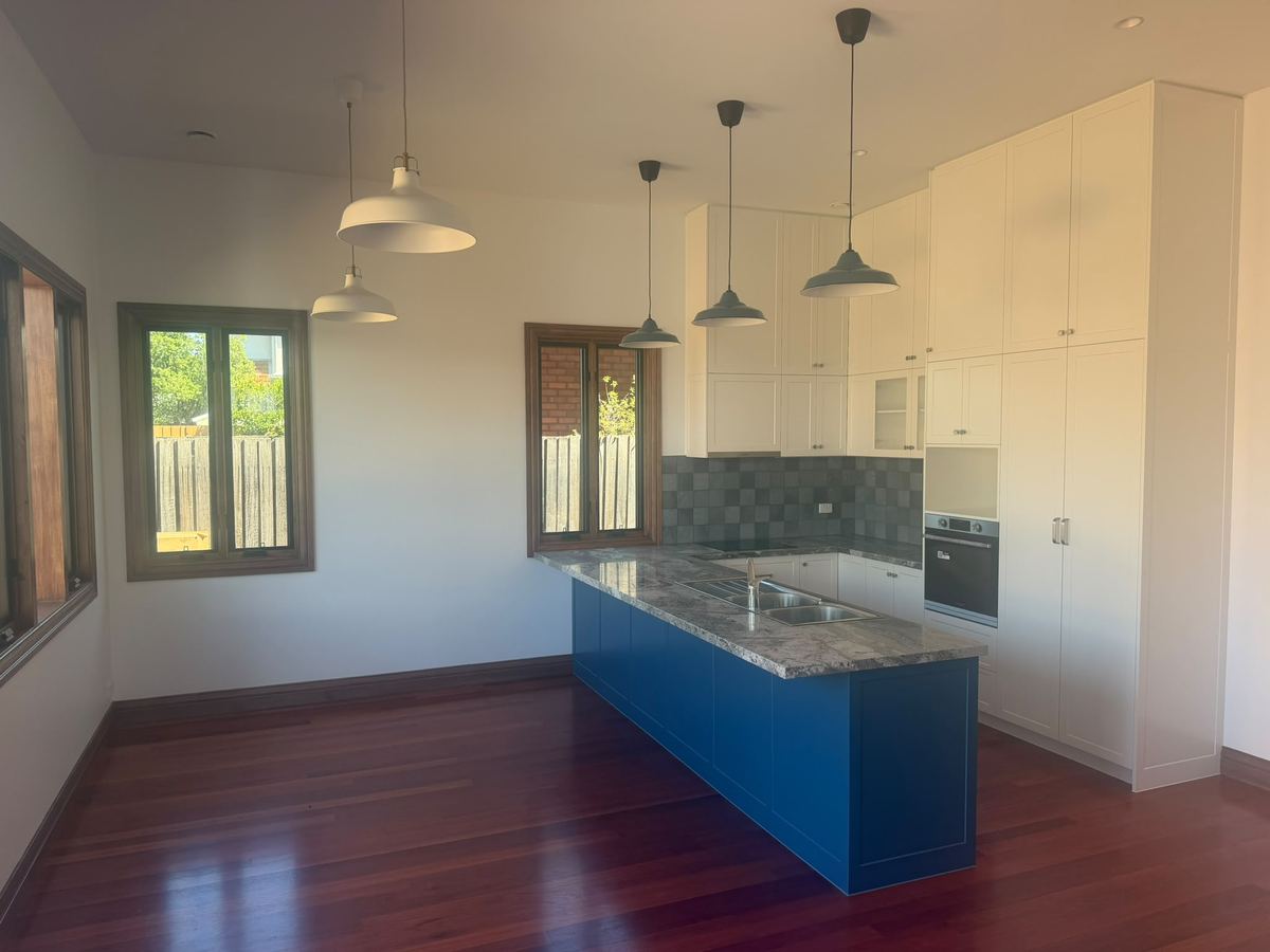 Kitchen with white joinery, a blue island and timber framed windows