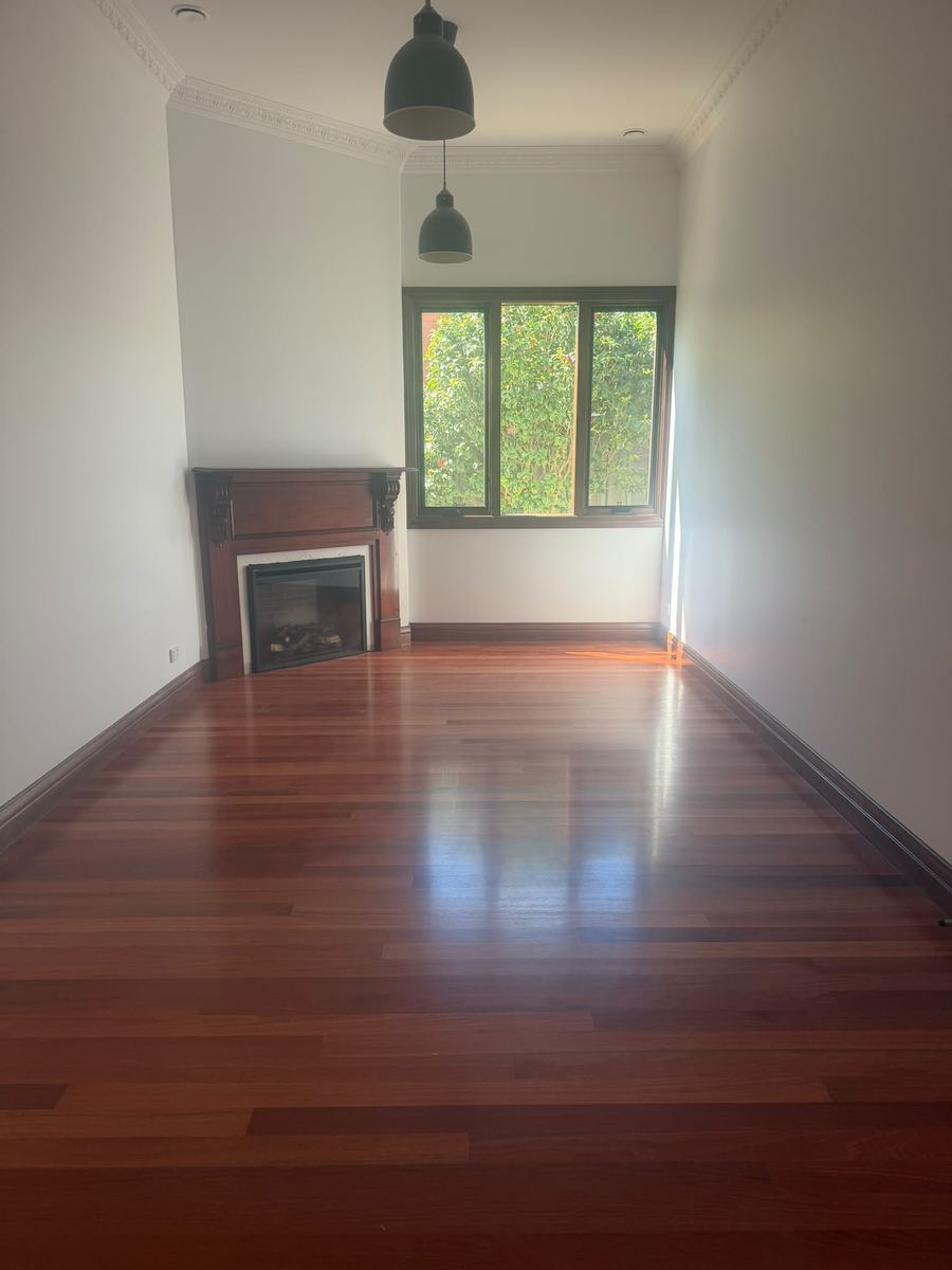 Period living room with a timber fireplace surround, high ceilings and polished floorboards