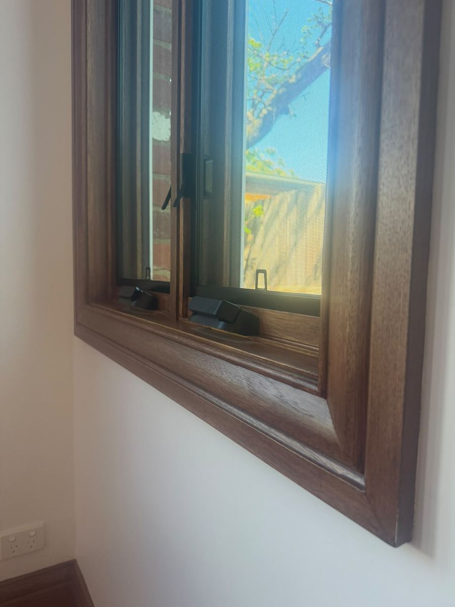 Close view of a stained timber window reveal and sash