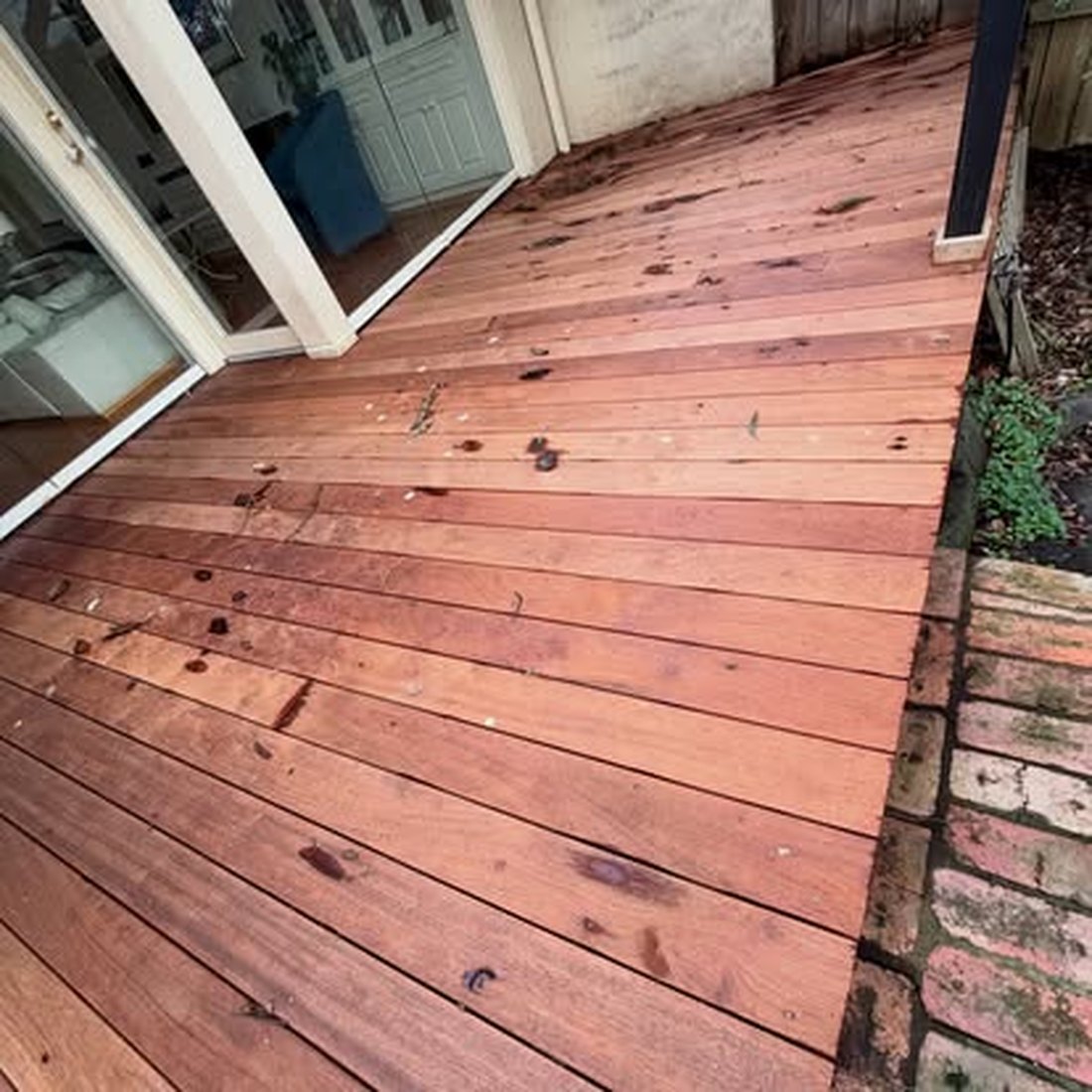 Finished timber deck with a curved edge, oiled a deep red brown