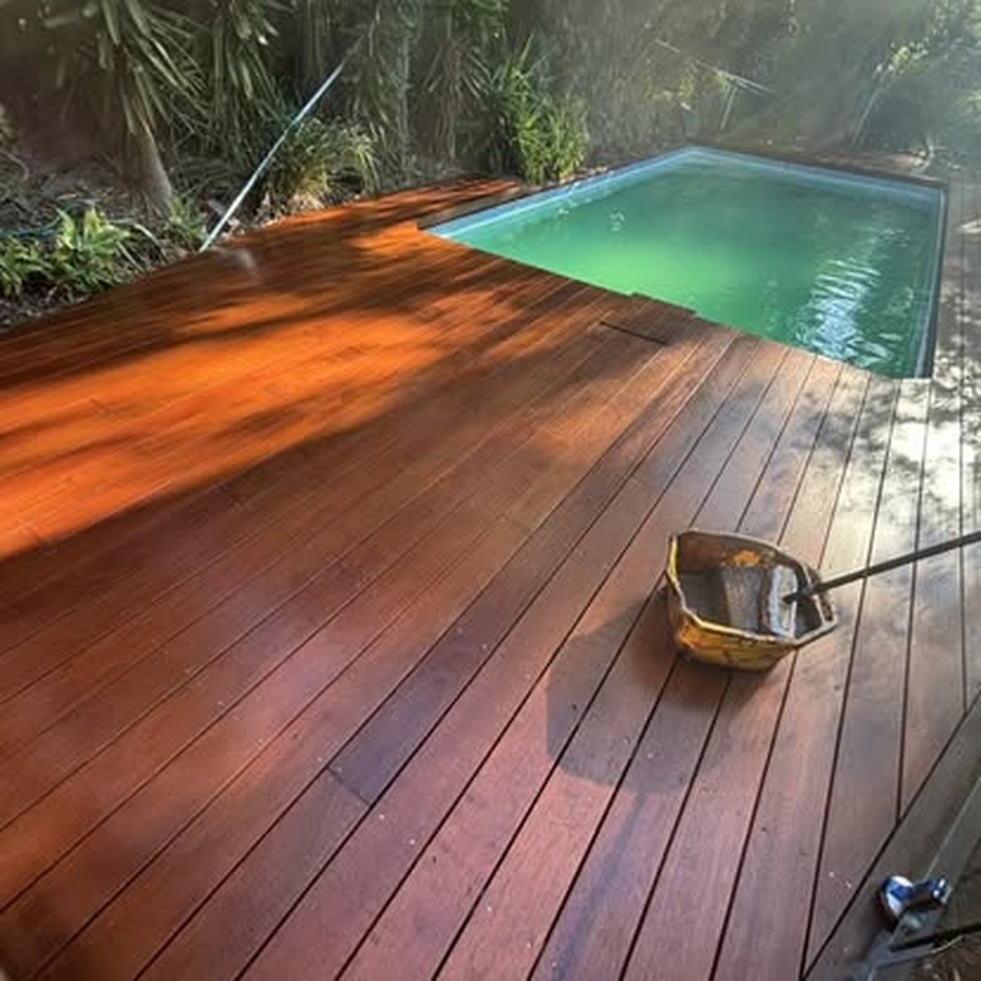 Timber deck part way through being oiled, with the tin and brush on the boards