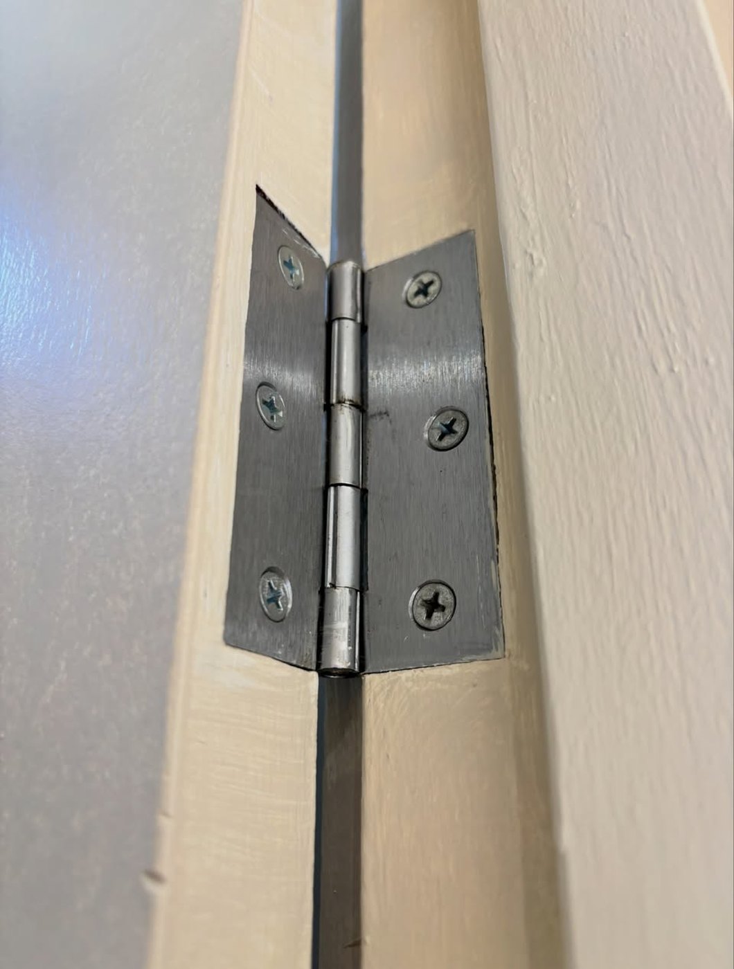 Close up of a door hinge on a freshly painted door frame