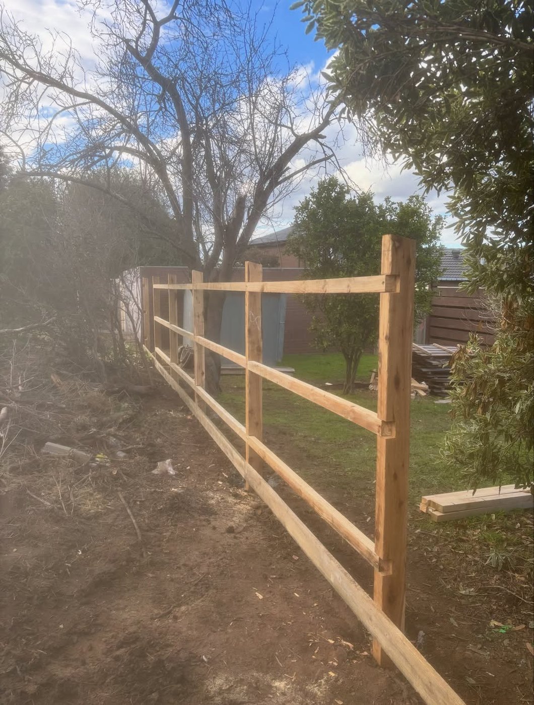 New timber post and rail fence with gum trees behind