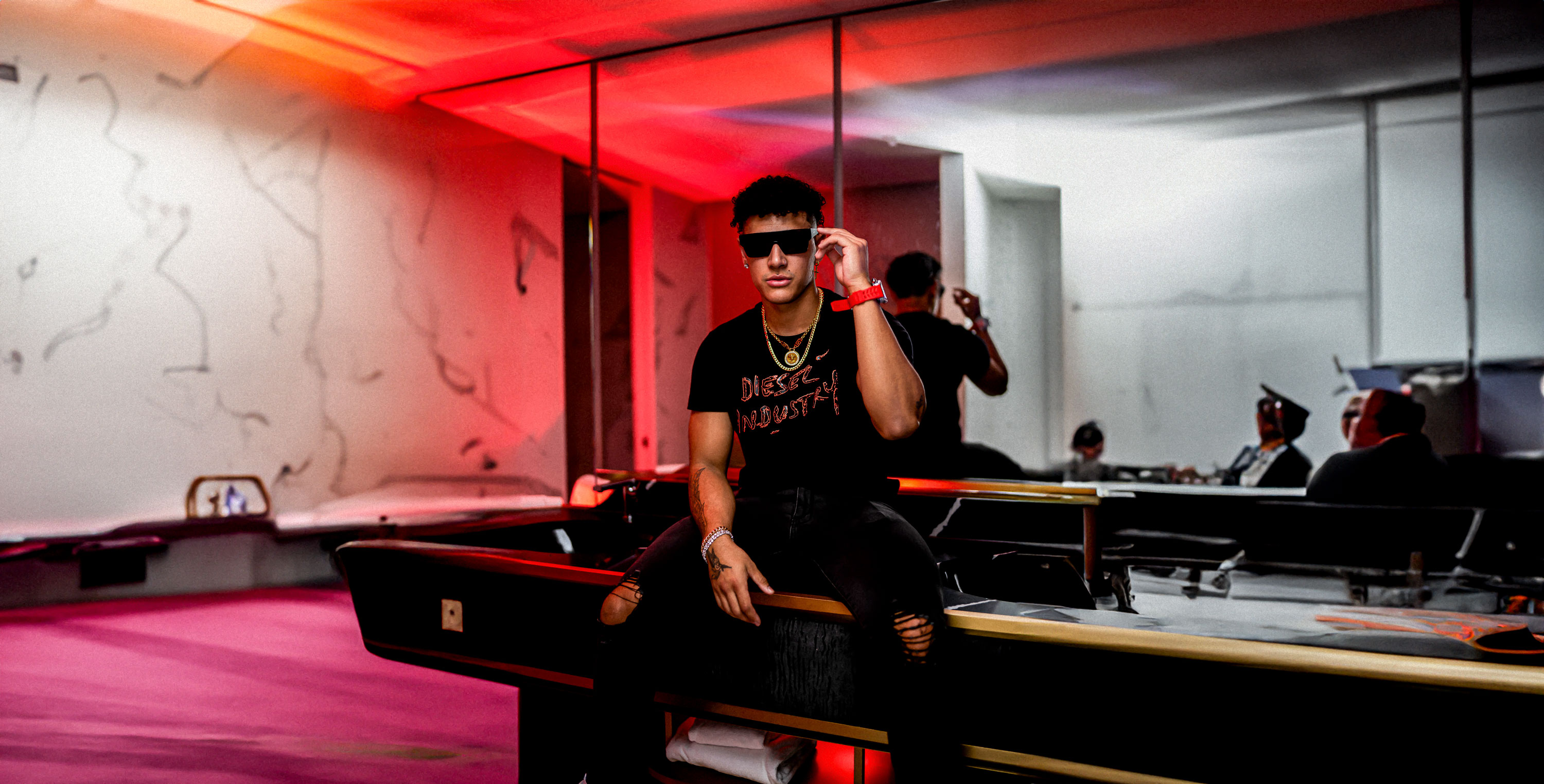 Seated on a pool table in a red lit lounge